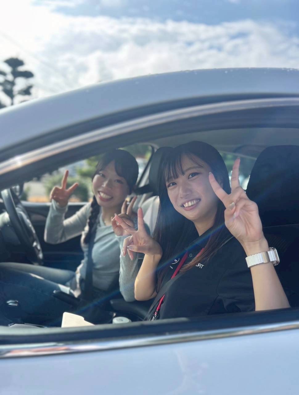 筑後自動車学校の教習車内で笑顔でピースサインをする教習生たち